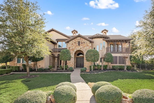 mediterranean / spanish house featuring a balcony and a front lawn