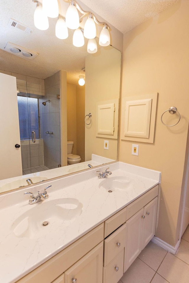 bathroom with toilet, a textured ceiling, walk in shower, tile patterned flooring, and vanity