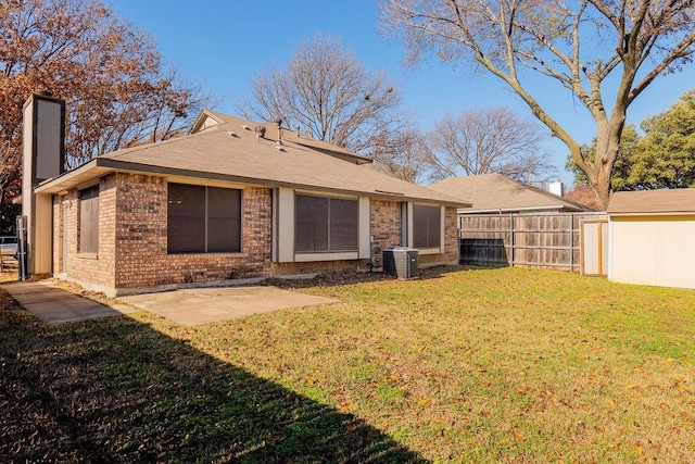 rear view of property with cooling unit, a patio area, and a lawn