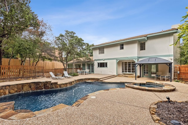 view of pool featuring a fenced backyard, a pool with connected hot tub, and a patio