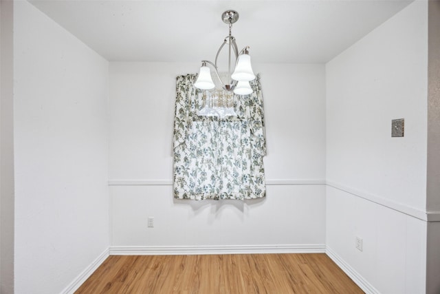 unfurnished dining area featuring hardwood / wood-style flooring and a notable chandelier