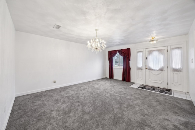 foyer entrance featuring a notable chandelier and dark colored carpet