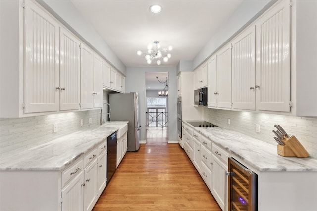 kitchen featuring white cabinetry, black appliances, a chandelier, and beverage cooler