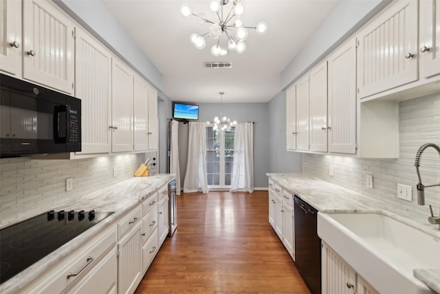 kitchen with decorative light fixtures, sink, white cabinets, black appliances, and a chandelier