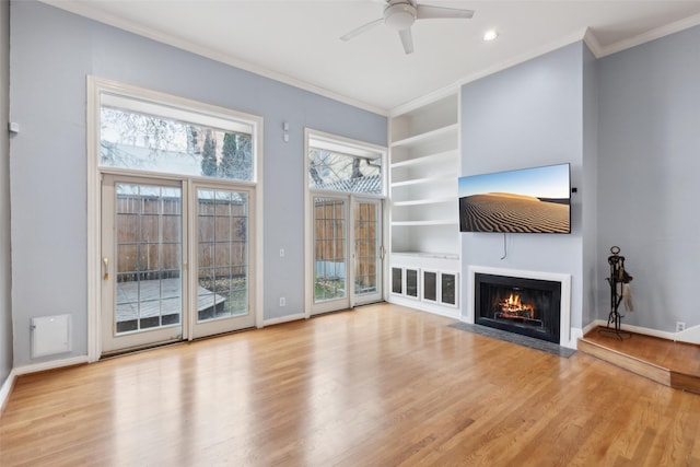 unfurnished living room featuring light hardwood / wood-style floors, built in features, crown molding, and ceiling fan