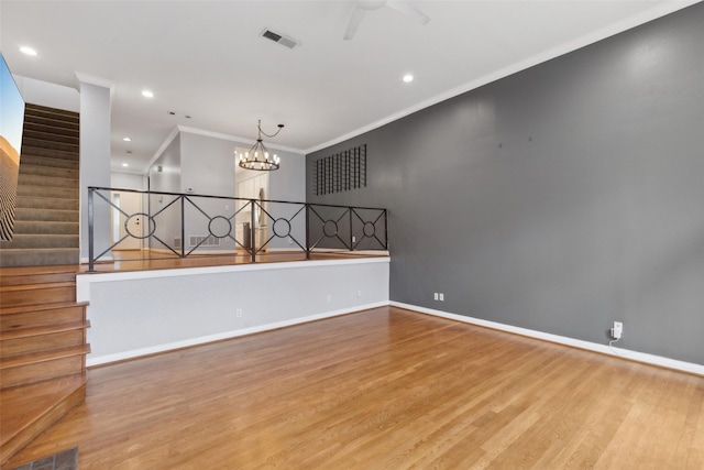 unfurnished room with ceiling fan with notable chandelier, ornamental molding, and light hardwood / wood-style floors