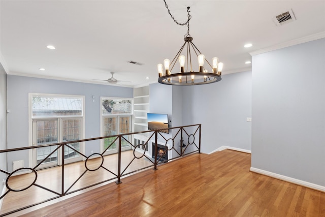 spare room with built in shelves, light hardwood / wood-style flooring, ceiling fan, and ornamental molding