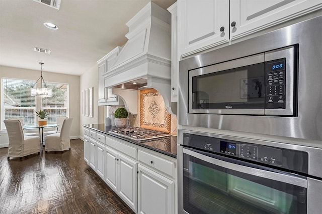 kitchen featuring pendant lighting, premium range hood, white cabinetry, and stainless steel appliances