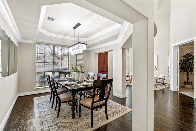 dining area featuring dark wood-type flooring, crown molding, and a raised ceiling