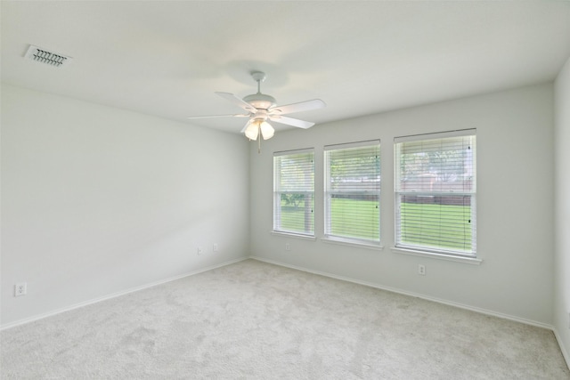 carpeted empty room with ceiling fan and a wealth of natural light