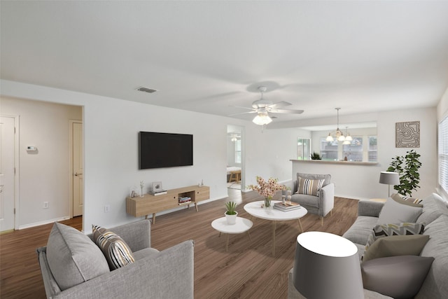 living room featuring ceiling fan with notable chandelier and dark hardwood / wood-style flooring