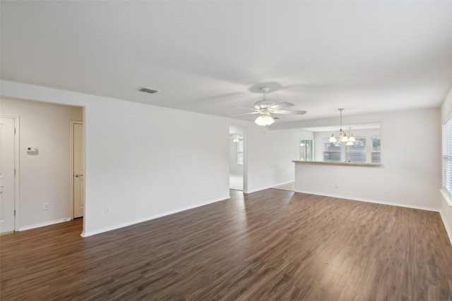 empty room with ceiling fan with notable chandelier and dark wood-type flooring