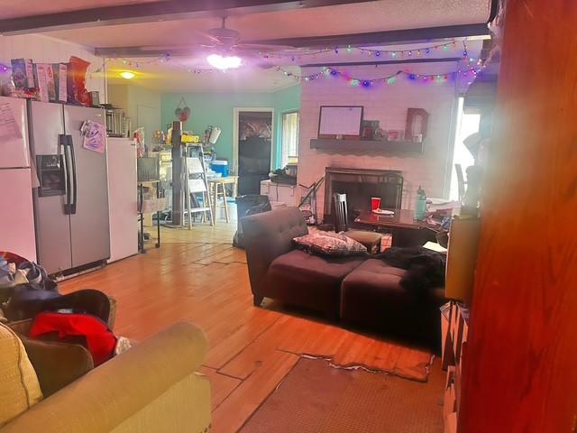 living room with ceiling fan, beam ceiling, and hardwood / wood-style floors