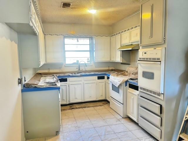 kitchen featuring white cabinetry, sink, white appliances, and a textured ceiling