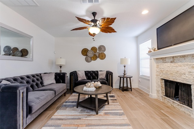 living room with ceiling fan, light hardwood / wood-style floors, and a fireplace