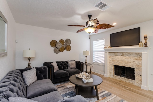 living room with ceiling fan, light hardwood / wood-style floors, and a fireplace