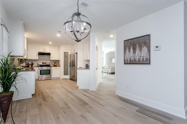 kitchen with pendant lighting, white cabinets, stainless steel appliances, tasteful backsplash, and a chandelier