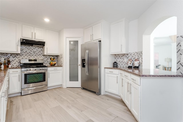 kitchen with white cabinets, appliances with stainless steel finishes, backsplash, kitchen peninsula, and stone counters