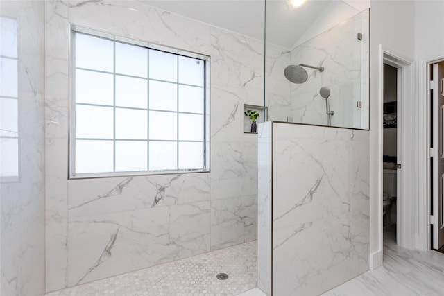 bathroom featuring a tile shower and lofted ceiling