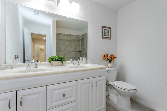 bathroom featuring toilet, vanity, a tile shower, and tile patterned flooring