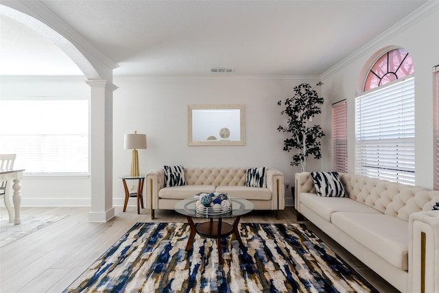 living room with wood-type flooring, a wealth of natural light, ornate columns, and crown molding