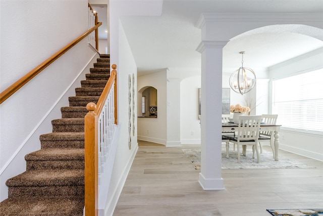 stairway with decorative columns, hardwood / wood-style flooring, a chandelier, and crown molding