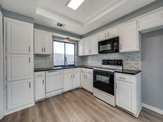 kitchen featuring white appliances, light hardwood / wood-style floors, white cabinetry, sink, and a raised ceiling