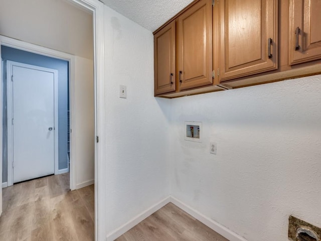 laundry room featuring a textured ceiling, cabinets, washer hookup, and light hardwood / wood-style floors