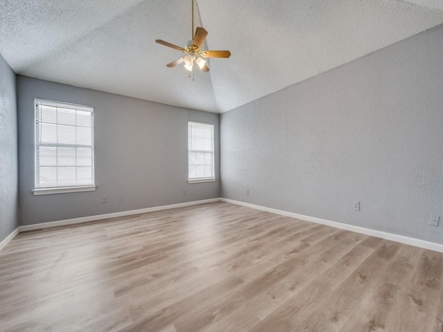 spare room with ceiling fan, a textured ceiling, light hardwood / wood-style flooring, and vaulted ceiling