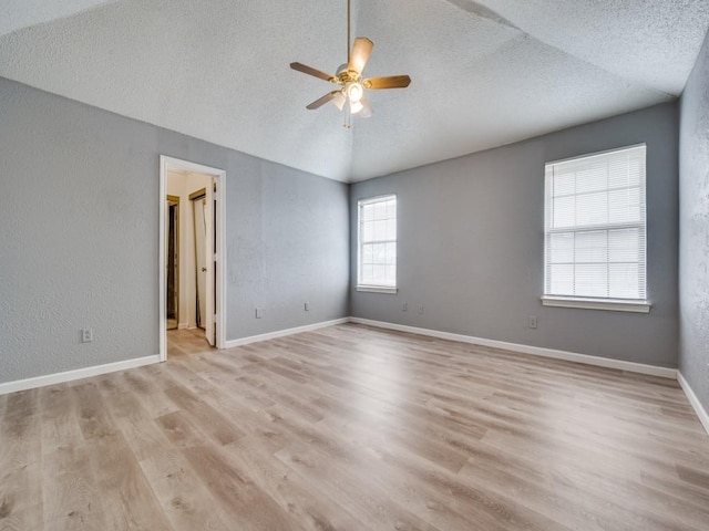 spare room featuring light hardwood / wood-style floors, a textured ceiling, ceiling fan, and vaulted ceiling