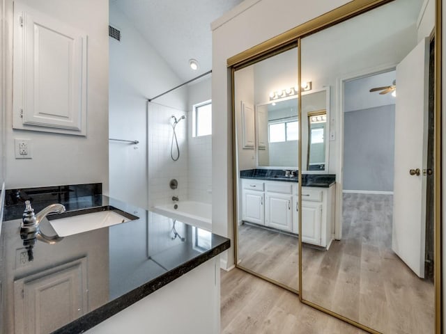 bathroom featuring hardwood / wood-style floors, vanity, lofted ceiling, and tiled shower / bath