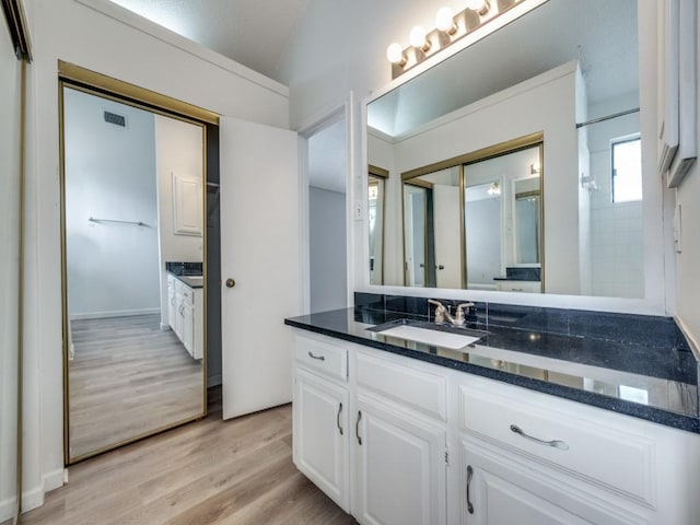 bathroom with vanity, hardwood / wood-style floors, and lofted ceiling