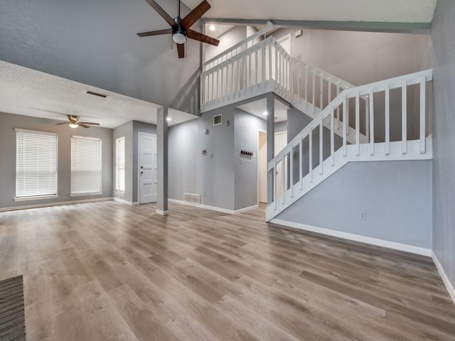 unfurnished living room with ceiling fan, high vaulted ceiling, a textured ceiling, and hardwood / wood-style flooring