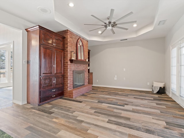 unfurnished living room featuring a raised ceiling, a wealth of natural light, and a fireplace