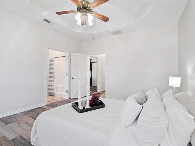 bedroom featuring ceiling fan, a raised ceiling, and hardwood / wood-style floors