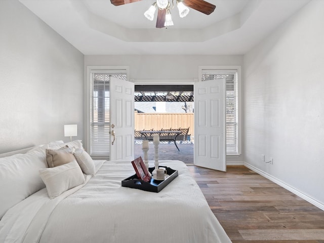 bedroom featuring hardwood / wood-style flooring, ceiling fan, and a raised ceiling