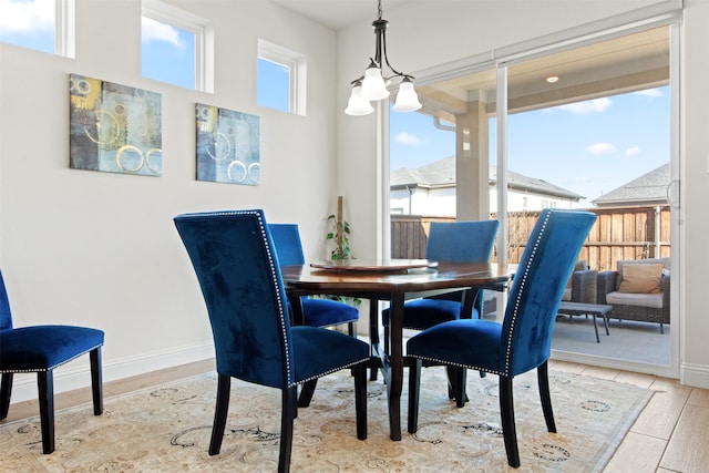 dining area featuring a healthy amount of sunlight, light hardwood / wood-style flooring, and an inviting chandelier