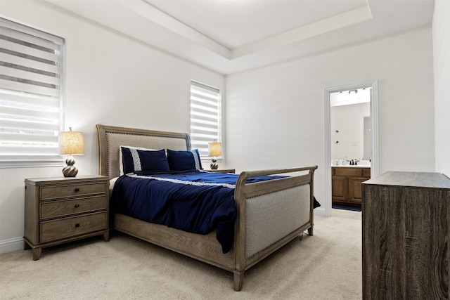 carpeted bedroom with sink, connected bathroom, and a tray ceiling