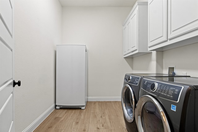 washroom featuring cabinets, light wood-type flooring, and washing machine and clothes dryer