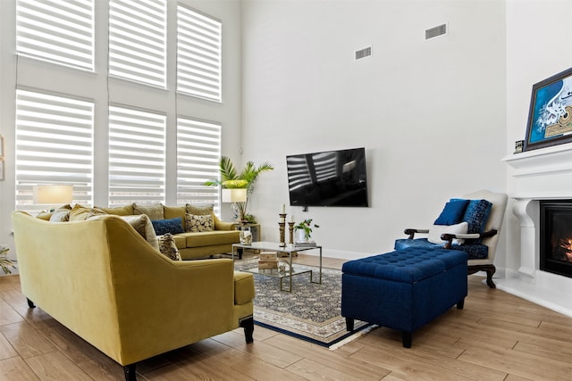 living room with hardwood / wood-style floors and a towering ceiling