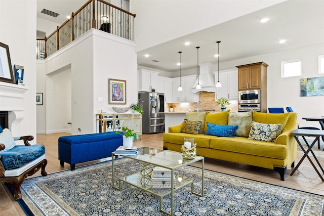 living room featuring sink, light hardwood / wood-style floors, and a towering ceiling