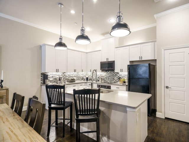 kitchen featuring white cabinetry, black refrigerator, hanging light fixtures, and a breakfast bar