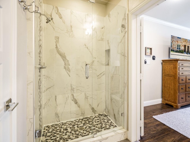 bathroom featuring ornamental molding, wood-type flooring, and a shower with shower door