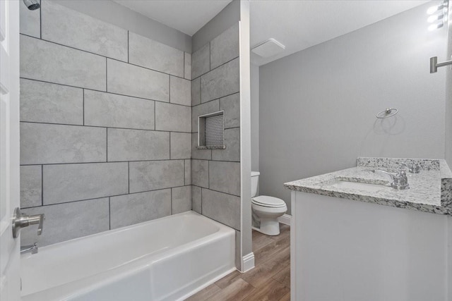 full bathroom featuring hardwood / wood-style floors, toilet, tiled shower / bath, and vanity