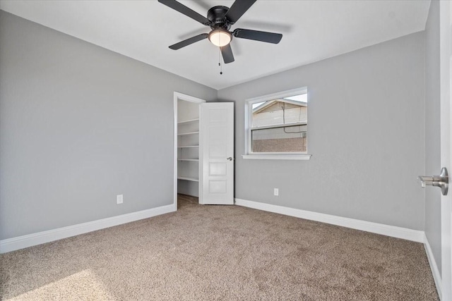 unfurnished bedroom featuring a closet, ceiling fan, a spacious closet, and carpet floors