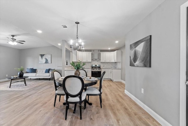 dining space featuring light wood-type flooring and ceiling fan with notable chandelier