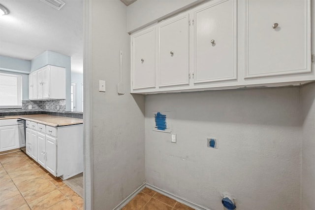 clothes washing area with hookup for an electric dryer, light tile patterned floors, and cabinets