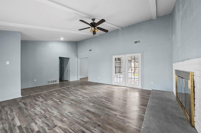 unfurnished living room featuring a towering ceiling, wood-type flooring, french doors, ceiling fan, and beam ceiling