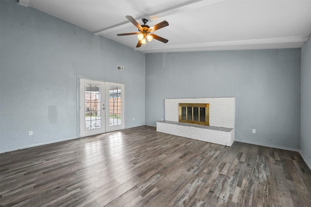 unfurnished living room featuring french doors, ceiling fan, dark hardwood / wood-style floors, a brick fireplace, and beam ceiling