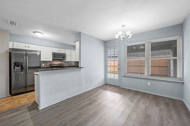 kitchen with a notable chandelier, appliances with stainless steel finishes, white cabinets, decorative light fixtures, and kitchen peninsula